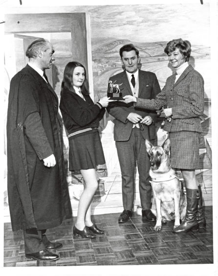 1969: In the second of two ceremonies at Mackie Academy, Stonehaven, yesterday, Miss Pearl Murray, woman's editor of the Press and Journal, hands over the replica of a guide dog to pupil Eileen Gibbons. The rector, Mr Ian Gilroy (left) and Mr Alec Duguid with his guide dog Shona, look on. The school had handed over to Miss Murray two cheques totalling more than £500 for the Pearl Murray Youth Project for Guide Dogs.