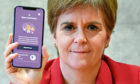 First Minister Nicola Sturgeon views the new Covid-19 track and trace app on a phone at the Scottish Parliament in Edinburgh.