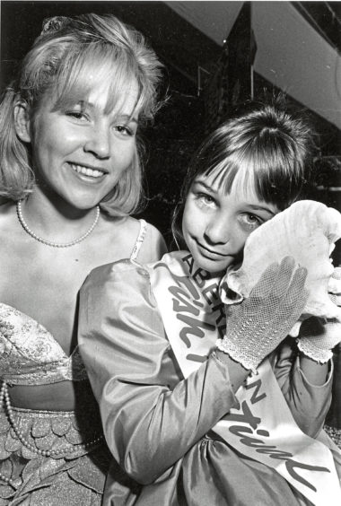 1990 - Listening for the sound of the sea in a big  shell is 10-year-old festival princess Danielle  Maloney, with mermaid Yvonne Collins