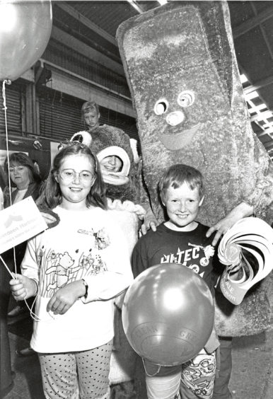 1990 - Harry Haddock and Charlie Chip say hello to  Kirriemuir siblings Fiona, 11, and David Glen,  8, who were visiting the fish festival