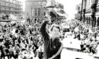 A fresh-faced Alex Ferguson holds aloft the Premier League championship trophy at the Castlegate in front of cheering fans.