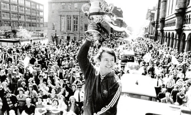 A fresh-faced Alex Ferguson holds aloft the Premier League championship trophy at the Castlegate in front of cheering fans in 1980. Image: Aberdeen Journals