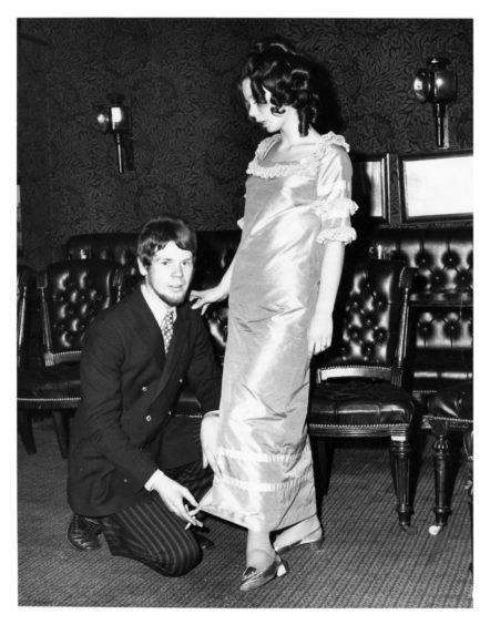 Bill crouched in front of a woman wearing a silk dress