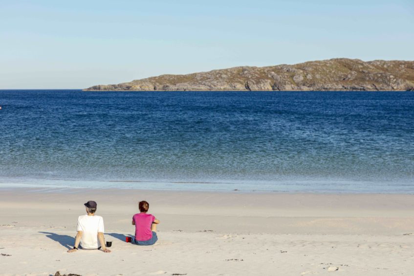 Two people sitting on Achmelvich beach.