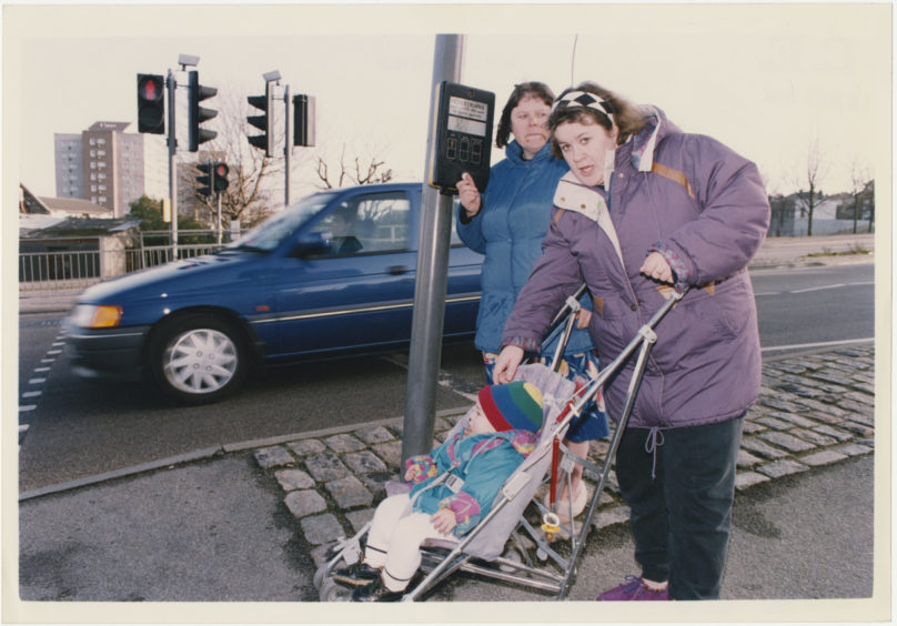 Mrs Sheila Addison presses the button at the pedestrian crossing as her daughter, Rosline, prepares to cross North Anderson Drive with her toddler Jayson.  17 November 1992.