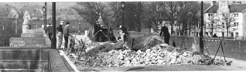 1960: The old Bridge of Dee, Aberdeen, is closed to traffic meantime while workmen make trial holes on the road-way. This is to allow engineers to ascertain the condition of the arches which support the centuries old bridge.