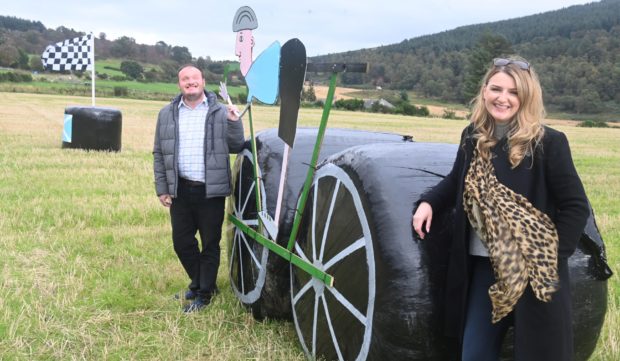 Jenna and Duncan Ross besides Tour of Britain hay bale display in Tarland