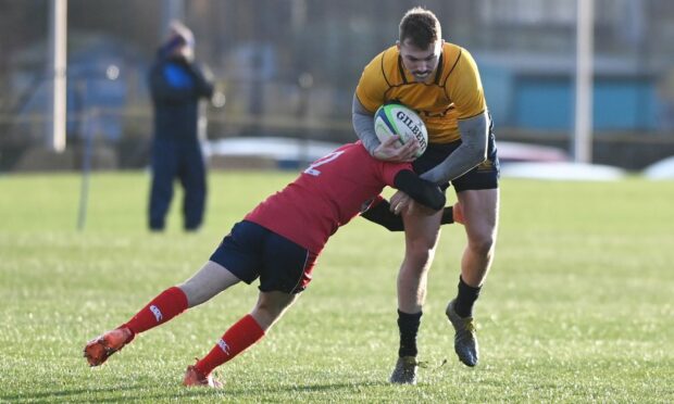 Gordonians' Angus Winning powers forward despite the efforts of Newton Stewart's Jack Gaw.