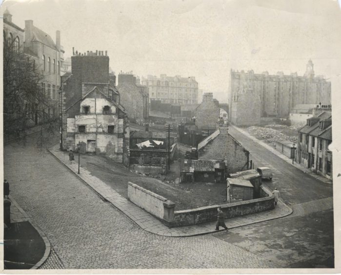 1956: The Denburn area in 1956. To the right, the Upper Denburn is being demolished and all the other buildings in foreground and middleground are doomed. Gas lamps and granite setts are still in evidence. A bus station was planned for this site but the scheme was planned for this site but the scheme was abandoned and the bus station built instead in Guild Street.