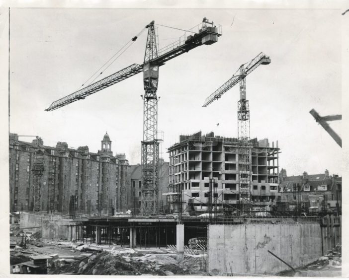 1971: Cranes tower over Aberdeen's Upper Denburn to service work on the eighth floor of a block of flats which will eventually rise to 22 storeys. Associated with the skyscraper is a children's play area, a 600 vehicle car park, and on top of that, the city's first area health centre.