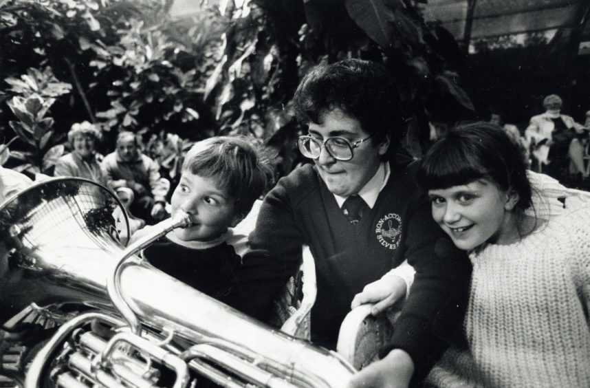 1988: Kevin Horne (5), has a go at producing a note on the euphonium, watched by his mum, Mrs Lesley Horne, Aberdeen, and his sister, Jill (7). The family were at the Winter Gardens in the Duthie Park where the Bon Accord Silver Band were providing Music by Candlelight.