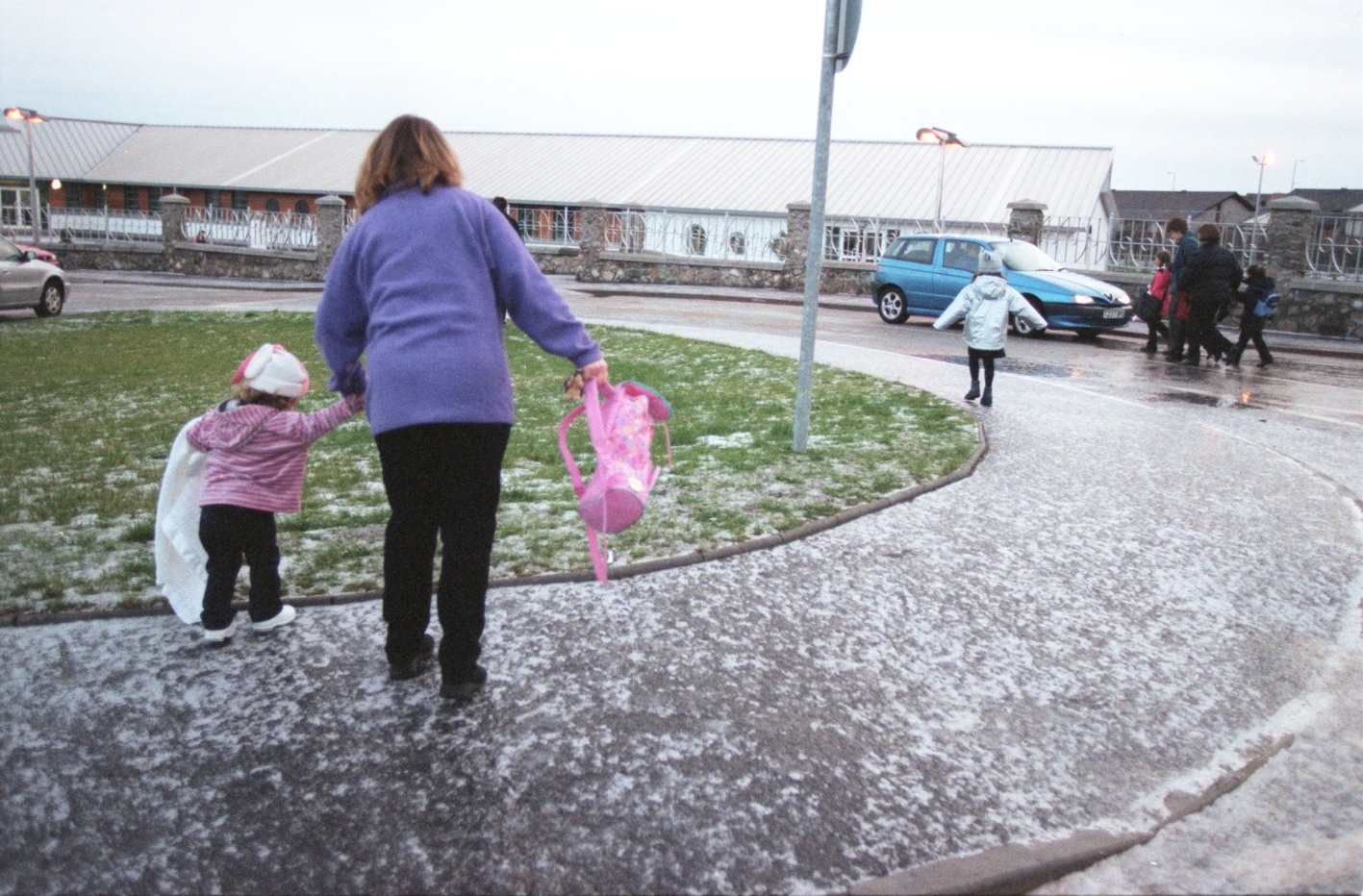 A mum is forced  to take her daughter on to the grassed area away from the  ice-covered pavement.