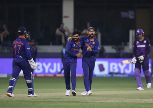 India's Ravindra Jadeja without cap, celebrates with captain Virat Kohli the dismissal of Scotland batter Matthew Cross