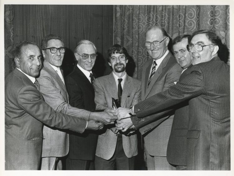 1986: Operations manager with Grampian Transport Mr Colin Smith (centre) presents the six retiring bus inspectors with their farewell gifts of wallets and notes. From left are: Inspector Charles Keenon, senior inspectors Arthur Burnett and George Tindall, chief inspector George Filby and senior inspectors John McEwen and Walter Reid.