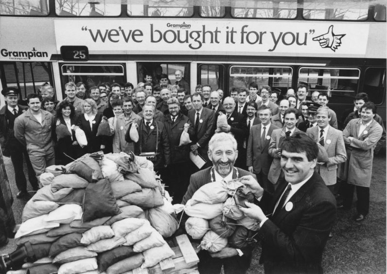 1989: Managing director of Grampian Transport Mr Moir Lockhead (right) hands over bags of cash for his stake in the buyout of the company to Grampian Regional Council convener Councillor Geoff Hadley. Lining up behind with their "fare" are staff from all departments of the new company.