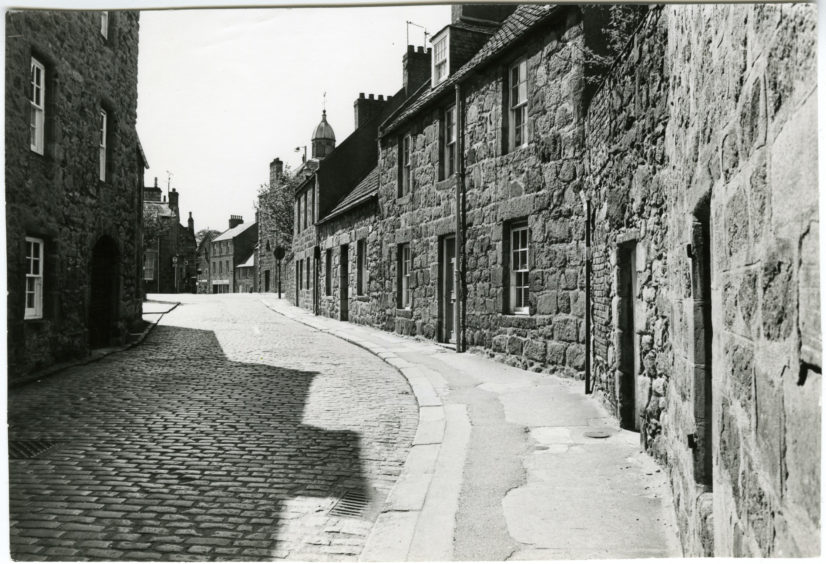 A view of the cottages on the cobbled Don Street, Old Aberdeen, Aberdeen, with long shadows being cast.