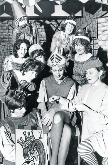1984: Lancelot has a hole in his tights and of course all the Knights of the Round Table gather round to give a helping hand. The Kemnay Drama Group rehearses for their Christmas panto "King Arthur and the Knights of the Round Table". Stella Youngson is Lancelot and busy with the needle is Ishbel Imrie as Ethelred.