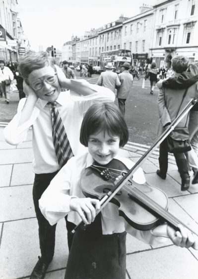 1989: Chin and bear it...Young violinist Anna Low, from Torphins, take a bow and tunes up to the mock consternation of Christopher Parker, Stonehaven, in Aberdeen's Union Street. Both are members of Aberdeen Music Centre preparatory string orchestra, who were playing in the city's Music Hall at the weekend to an audience of schoolmates, teachers and parents.