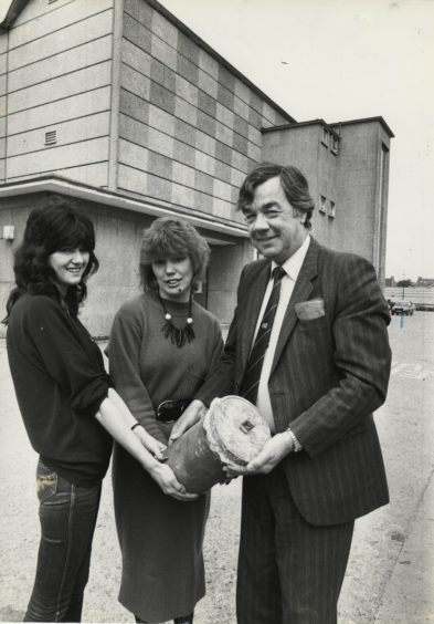1987 - Norco retail services controller Brian Blackmore gets a hand from office girls Elaine Mathieson, left, and Shona Kiloh to lift the time capsule outside Millbank House