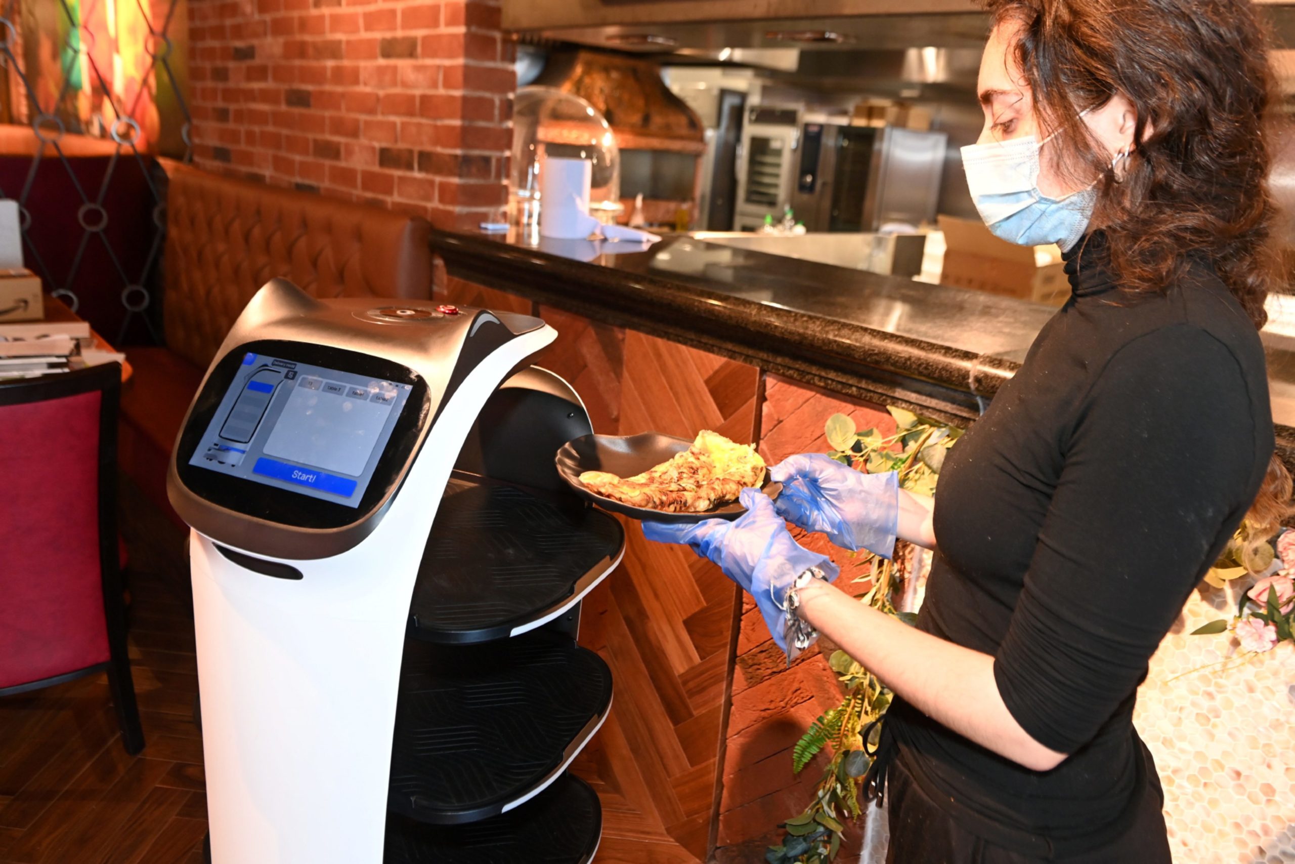 A member of staff places the food onto the robot which will take it to the customer's table.