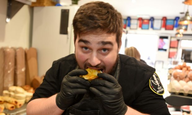 Shop apprentice Jay Sellick eats one of the mouthwatering pies at Lurch Monster's Tilly Butcher, Aberdeen.