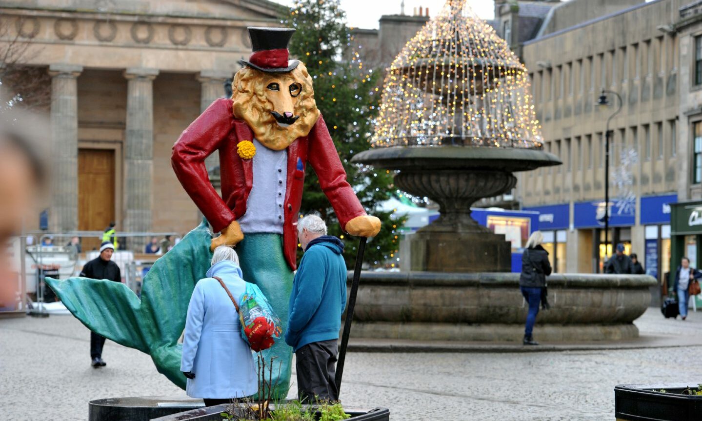 Dandy Lion in Elgin with two people looking at it. 