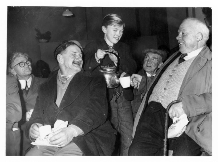 1963 - William Sutherland gets a cup of tea from 15-yearold Norman Anderson at the Christmas party at the Shiprow Tavern Pub as John Beange awaits his turn