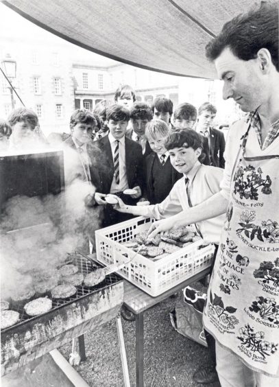 English teacher Michael Duncan and pupil Gregor Maxwell serve up some burgers to a group of hungry students at a barbecue