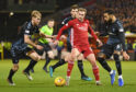 Aberdeen's James Wilson, centre, holds off Rangers' Filip Helander and Connor Goldson, right.
