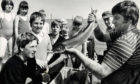A silver salmon from the nets at Aberdeen Beach holds the attention of youngsters and adults alike as fishermen Tommy Thomson and Bob Nicholson show the fish to the holiday makers