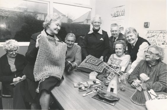 1981: Looking at one of the cardigans knitted at the Women's Royal Voluntary Services Friday (Disabled) Club, shown by deputy regional organiser Miss Ray Skinner, are some of the members and helpers at the weekly meeting.