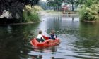 Two young boys enjoy the fine October weather by playing in one of the pedalos on the duck pond at the Duthie Park in 1990.