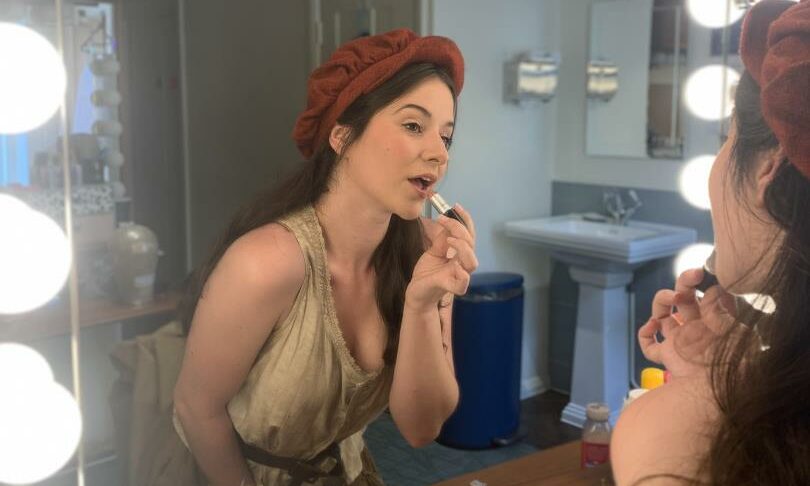 Jenna Innes in her Les Miserables costume applying her make up in the mirror. 