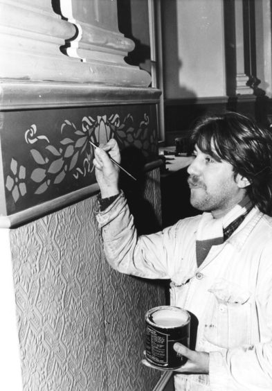 1986: Painter Douglas Styles touches up stencil work in the Music Hall auditorium