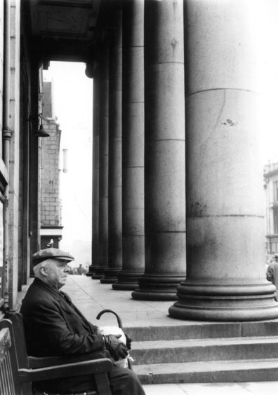 1961: A man stops for a rest on one of the seats outside the Music Hall