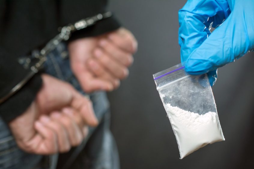 A packet of drugs with a man in handcuffs.