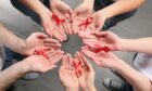 Detail of hands with red ribbons for World Aids Day and the importance of going for a HIV test in Aberdeen