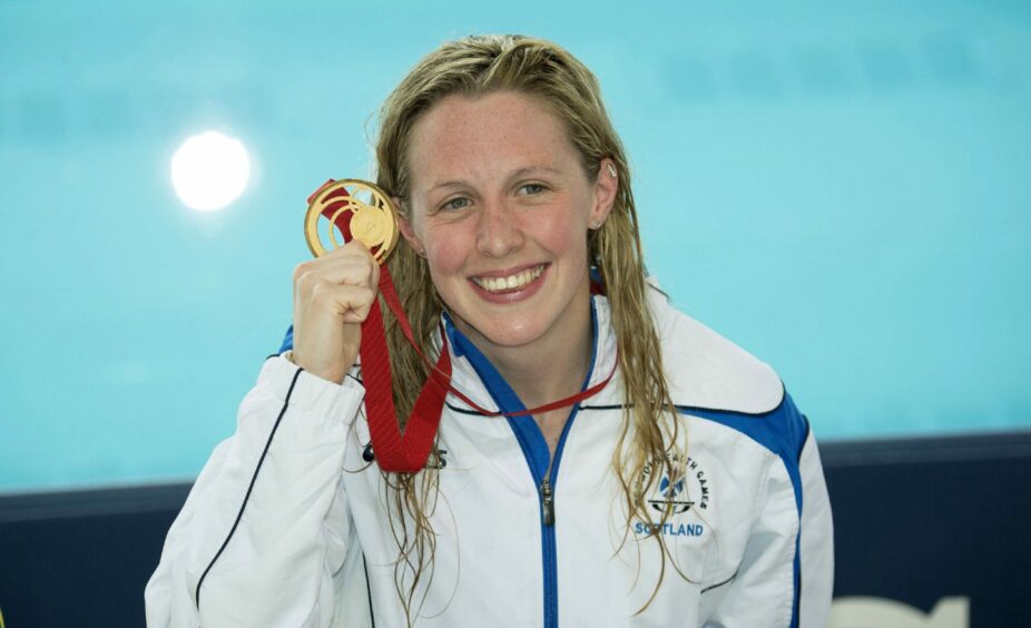 Hannah Miley smiling with her gold medal in hand 