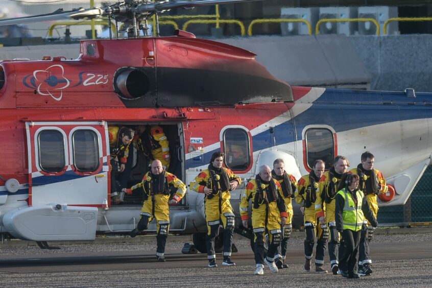 Offshore workers disembark from a helicopter at Aberdeen Heliport.