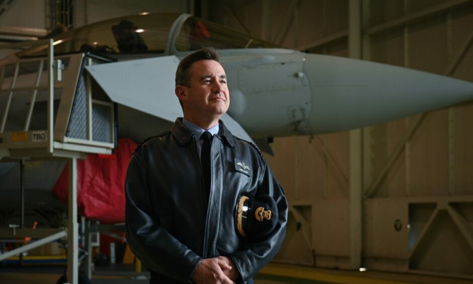 Group Captain Chris Layden stands to attention in front of a Typhoon. 