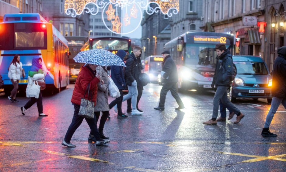 People with umbrellas cross the street in the rain