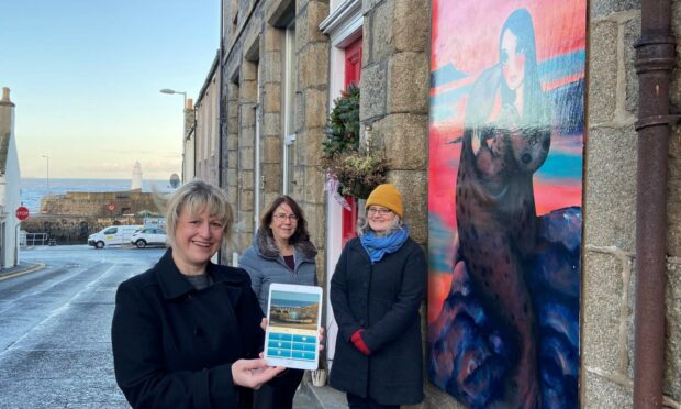 Vivien Rae, Lynn MacKinnon and Rachel Kennedy with the new app and one of the murals.
