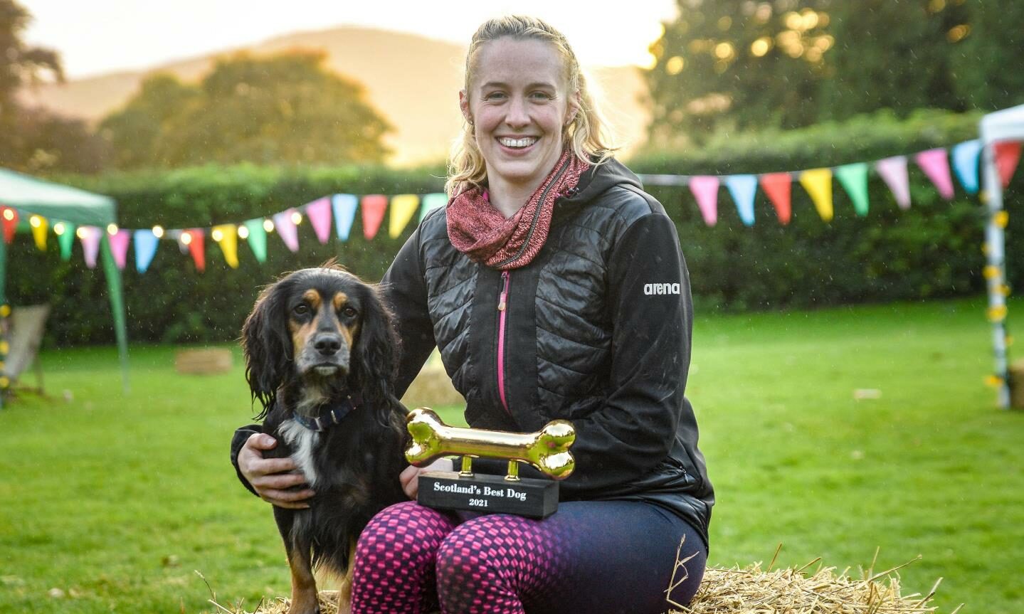 Hannah Miley with a dog and a golden bone trophy on her lap