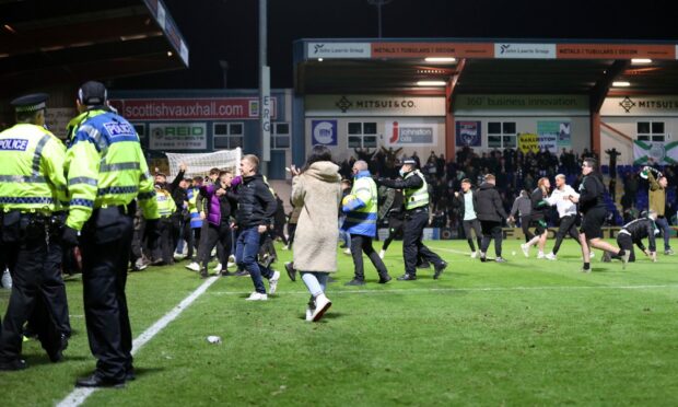 Celtic fans celebrate on the pitch at Victoria Park.