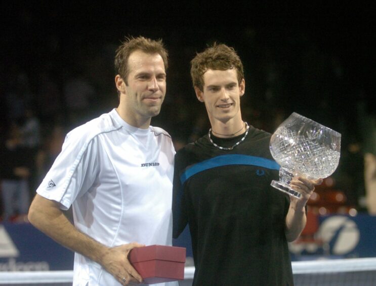 A young Andy Murray holding his trophy next to Greg Rusedski