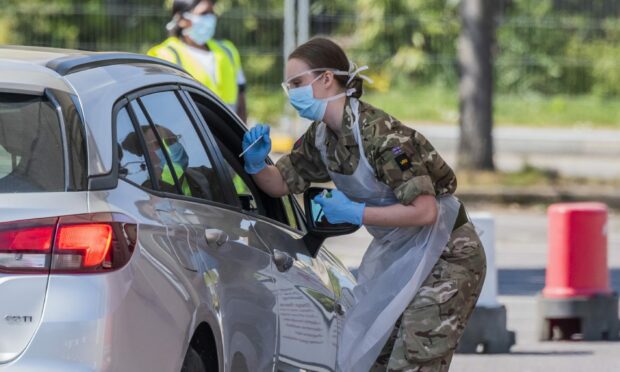 A military troop takes a Covid test through a car window.