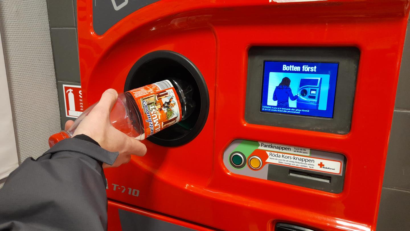 A bottle being inserted into a reverse vending machine in Sweden to be recycled