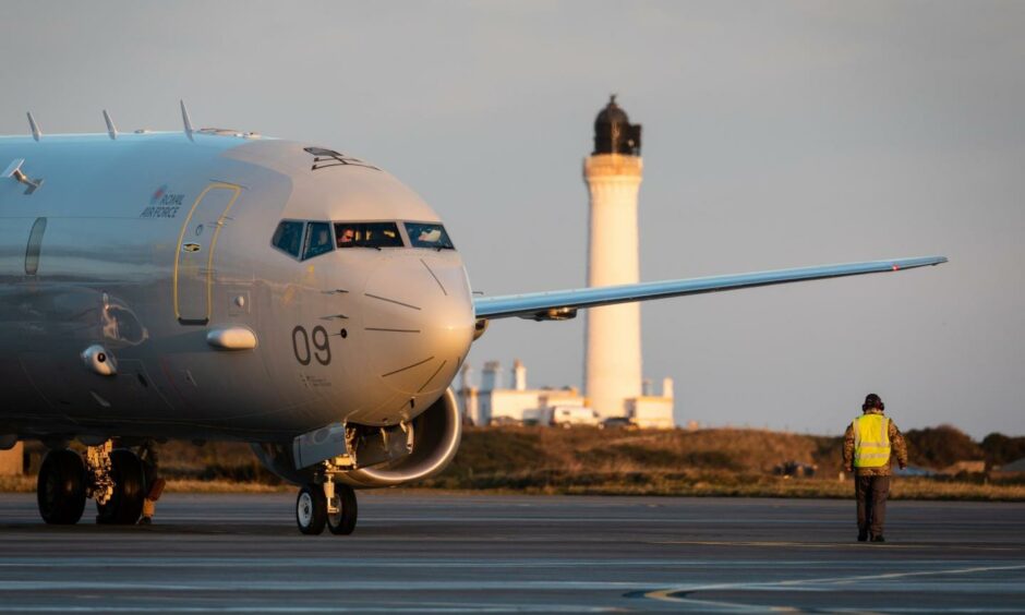 Poseidon plane on ground at RAF Lossiemouth with Covesea lighthouse behind.
