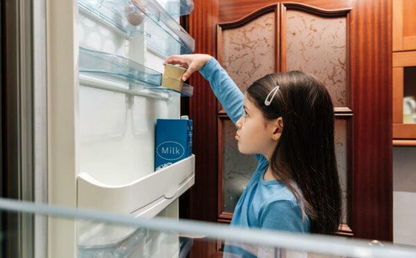 Little girl opening an empty fridge.