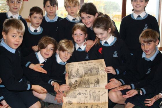 Year 6 students at Gordonstoun crowd around the 1922 newspaper.